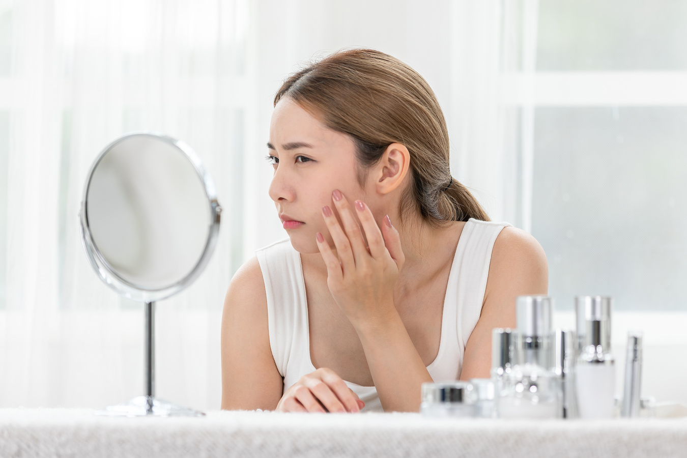 Asian young woman looking in mirror worry about pores facial skin problem with acne and dry skin. Self care and Skin care concept